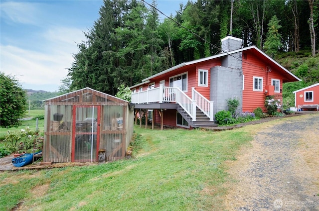 view of home's exterior featuring an exterior structure, a chimney, a lawn, an outdoor structure, and stairway