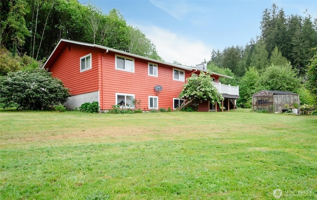 rear view of house with a greenhouse, a yard, an outbuilding, and a deck