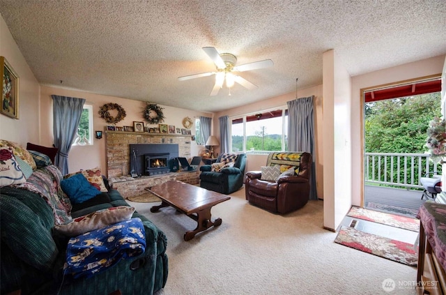 living area featuring a textured ceiling, ceiling fan, carpet, and a fireplace