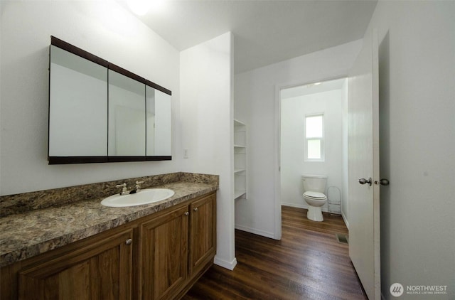 bathroom featuring wood finished floors, vanity, toilet, and baseboards