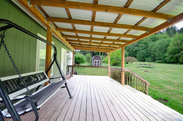 wooden terrace featuring a storage shed, a yard, and an outbuilding