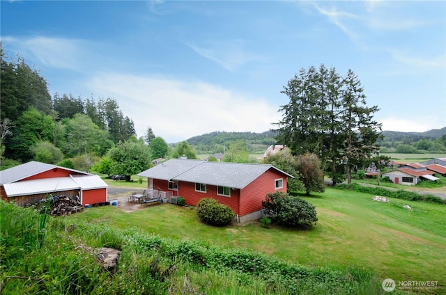 view of side of home featuring a lawn, a chimney, a detached garage, and a deck with mountain view