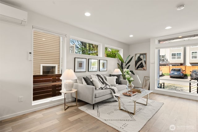 living area with recessed lighting, a wealth of natural light, light wood-style flooring, and a wall unit AC