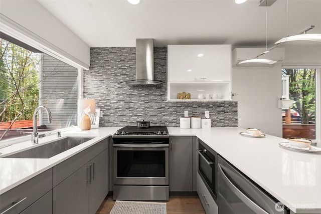 kitchen featuring gas range, wall chimney exhaust hood, gray cabinets, and a sink