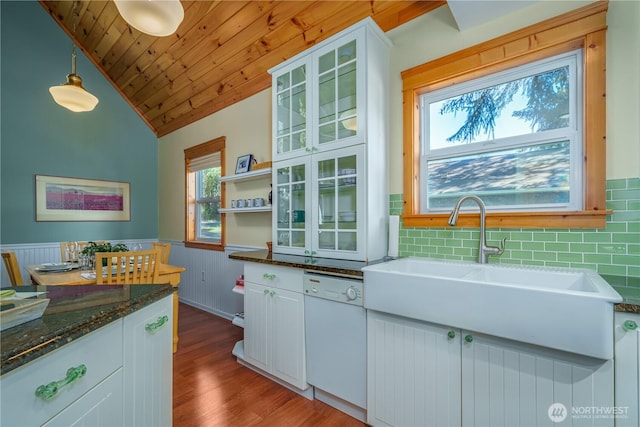 12916 91st Street Ct, Anderson Island, WA 98303 - kitchen featuring white dishwasher, wood finished floors, wainscoting, glass insert cabinets, and lofted ceiling