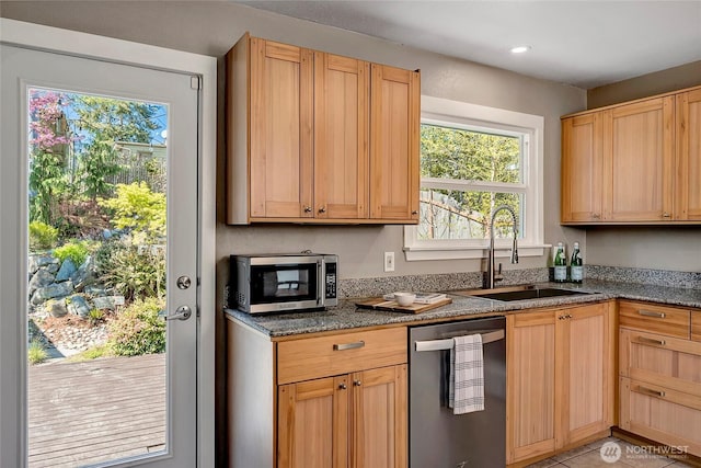kitchen featuring recessed lighting, dark stone countertops, stainless steel appliances, and a sink
