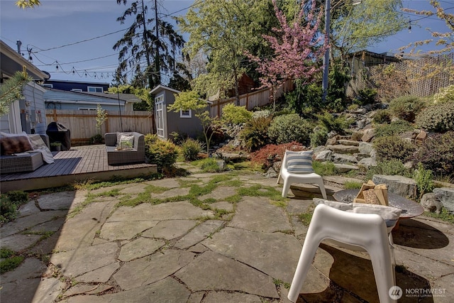 view of yard with a wooden deck, a fenced backyard, and a patio