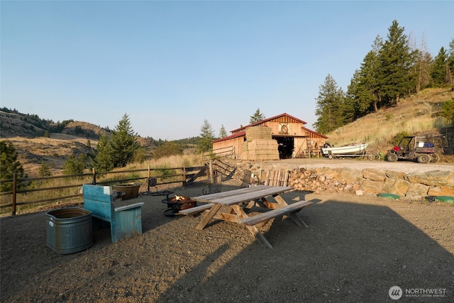 view of yard with an outdoor structure, fence, a barn, and an outdoor fire pit