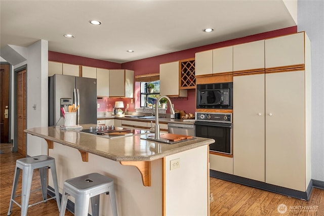 5201 Hyada Blvd NE, Tacoma, WA 98422 - kitchen featuring a center island, recessed lighting, light wood-style floors, a breakfast bar, and black appliances