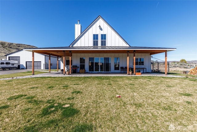 rear view of property featuring a lawn, a standing seam roof, board and batten siding, and metal roof