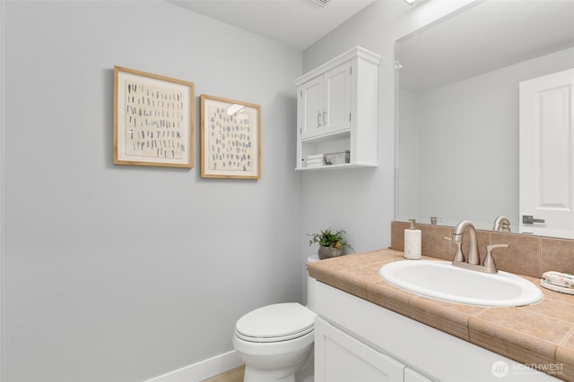 half bath featuring toilet, vanity, and baseboards