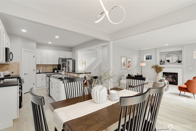 dining space featuring light wood-style flooring, recessed lighting, and a glass covered fireplace