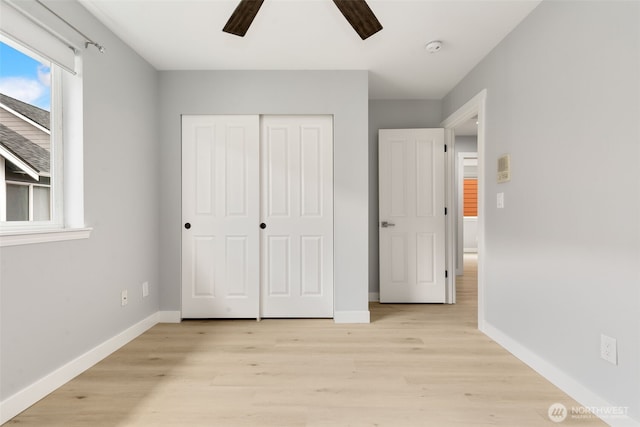 unfurnished bedroom featuring a closet, light wood-style flooring, baseboards, and ceiling fan