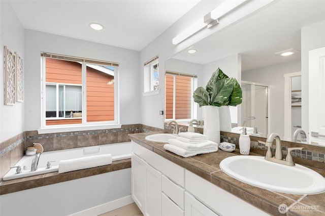 bathroom featuring a shower stall, a garden tub, double vanity, and recessed lighting