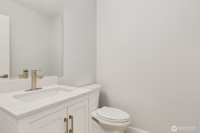 bathroom with toilet, baseboards, and vanity