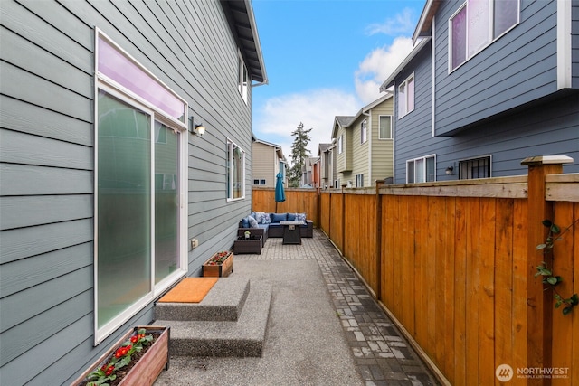 view of property exterior featuring outdoor lounge area, fence, a patio area, and a residential view