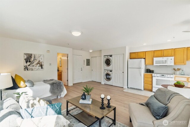 living room with recessed lighting, stacked washer / drying machine, and light wood-style flooring