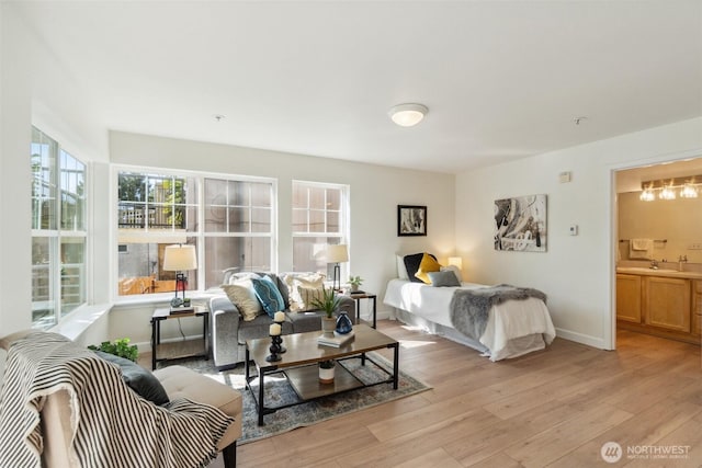 bedroom featuring light wood-type flooring, baseboards, and a sink