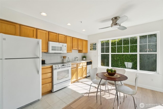 kitchen featuring recessed lighting, light countertops, a sink, white appliances, and decorative backsplash