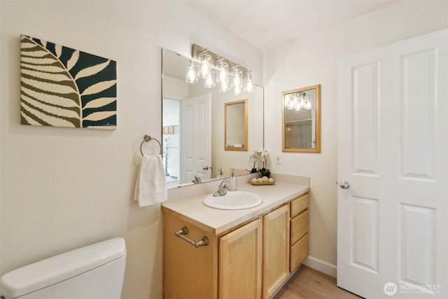 bathroom featuring wood finished floors, toilet, and vanity