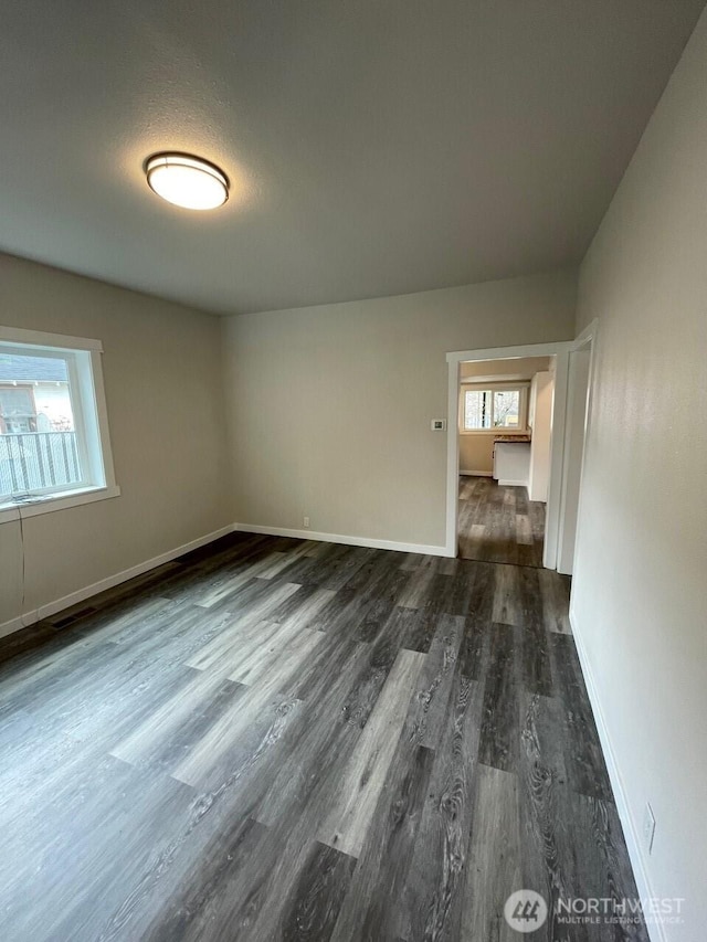 spare room with dark wood finished floors and baseboards