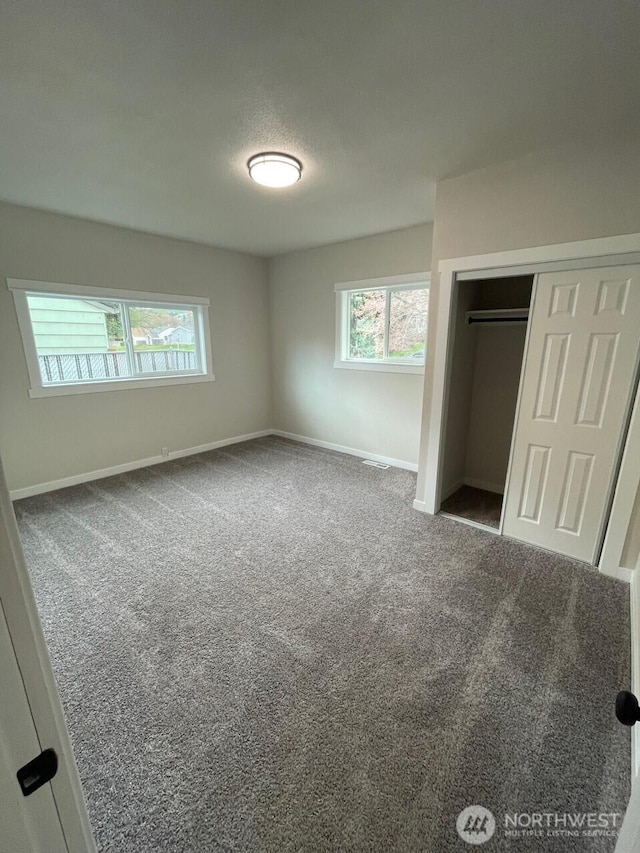 unfurnished bedroom featuring visible vents, baseboards, carpet floors, and a closet