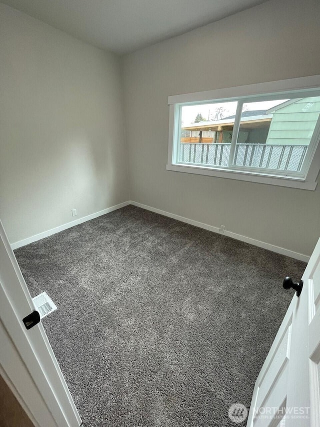 carpeted spare room featuring visible vents and baseboards