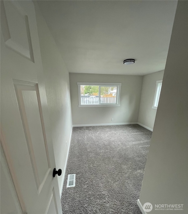 carpeted spare room featuring baseboards and visible vents