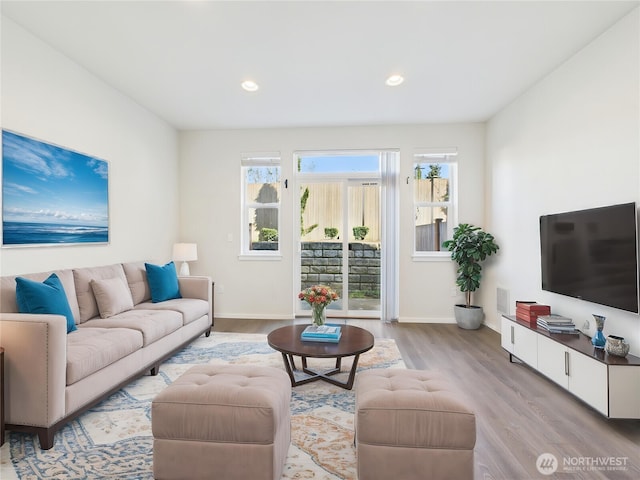 living room with light wood-style floors, plenty of natural light, and baseboards