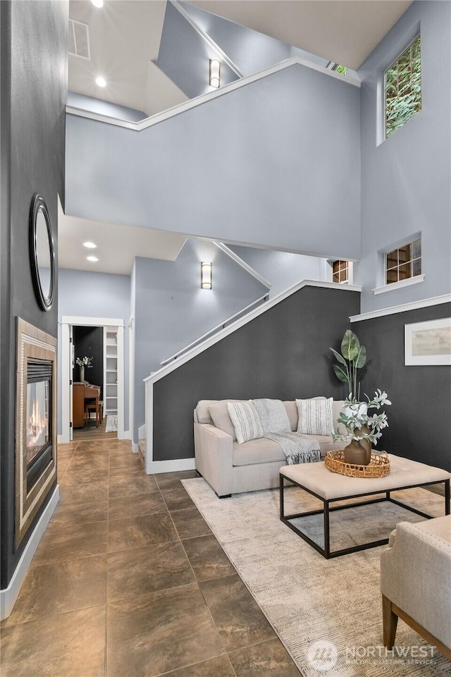 living room featuring a high ceiling, stairs, a fireplace, and baseboards