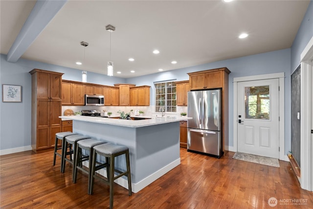 kitchen with stainless steel appliances, brown cabinetry, a sink, light countertops, and recessed lighting