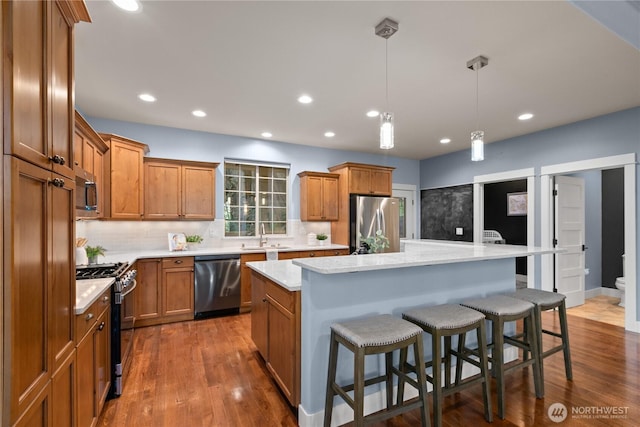 kitchen with stainless steel appliances, brown cabinetry, a center island, tasteful backsplash, and recessed lighting