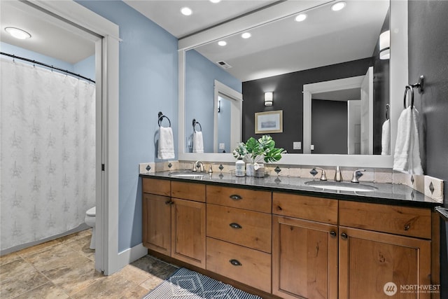 bathroom with double vanity, toilet, baseboards, and recessed lighting