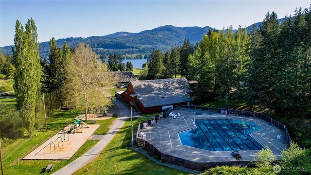 community pool with a mountain view, a forest view, and a yard