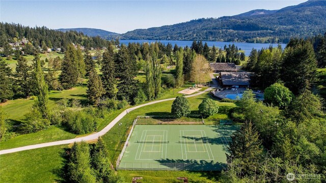 drone / aerial view of a heavily wooded area and a water and mountain view