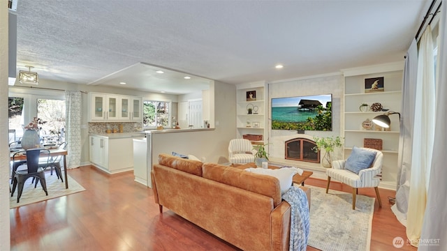 19134 SE May Valley Rd, Issaquah, WA 98027 - living room featuring a large fireplace, wood finished floors, recessed lighting, a textured ceiling, and built in shelves