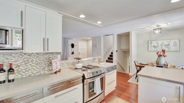 19134 SE May Valley Rd, Issaquah, WA 98027 - kitchen with appliances with stainless steel finishes, decorative backsplash, light countertops, light wood-style flooring, and recessed lighting