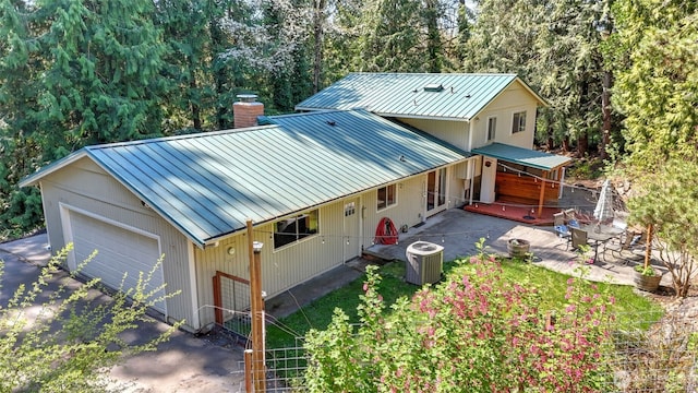 19134 SE May Valley Rd, Issaquah, WA 98027 - view of front facade featuring a chimney, central AC unit, a garage, metal roof, and a patio