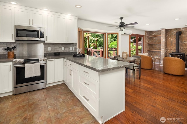 26032 5th Ave NE, Arlington, WA 98223 - kitchen with appliances with stainless steel finishes, a wood stove, a peninsula, decorative backsplash, and recessed lighting
