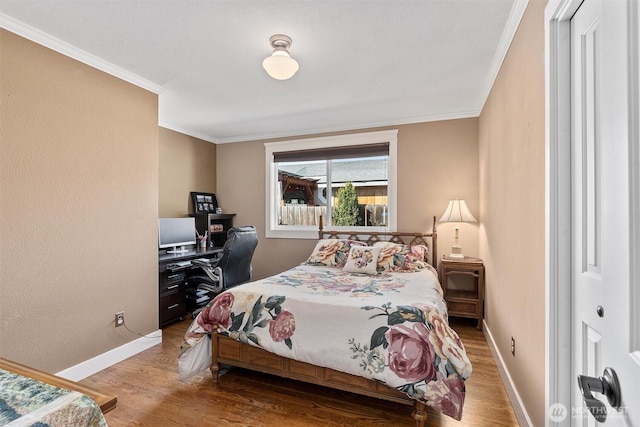 bedroom with wood finished floors, crown molding, and baseboards
