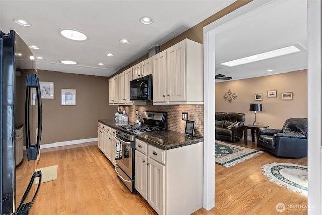 kitchen featuring light wood finished floors, dark countertops, white cabinets, and black appliances