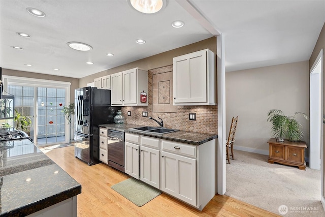 kitchen with a sink, white cabinetry, black appliances, and tasteful backsplash