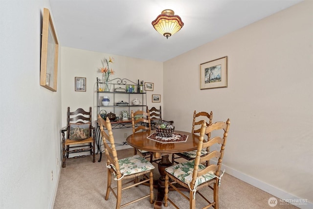 dining room featuring light colored carpet and baseboards