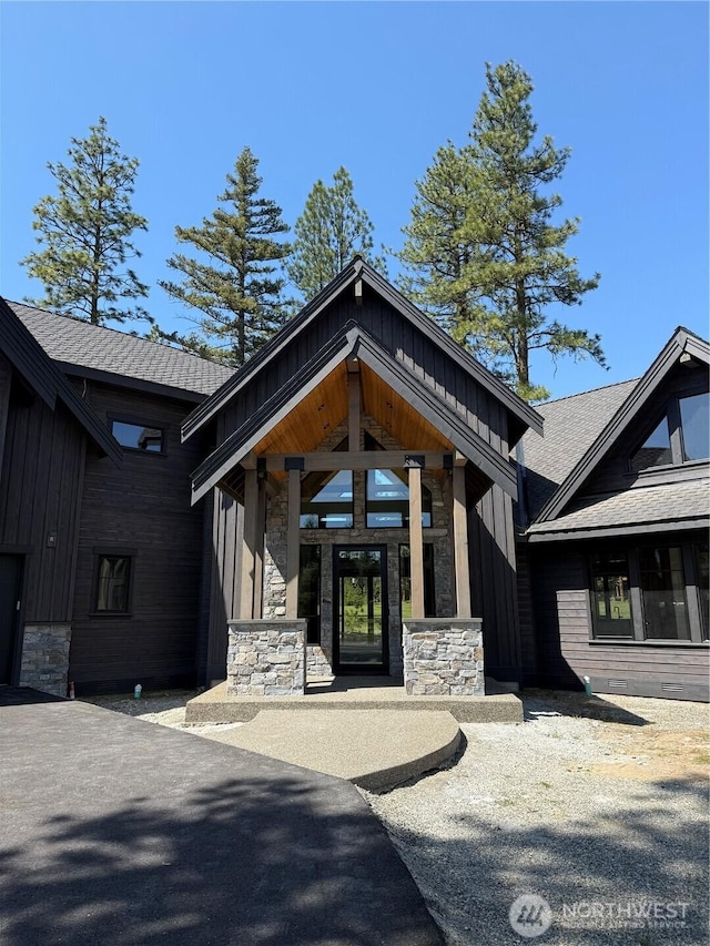 doorway to property featuring board and batten siding and stone siding