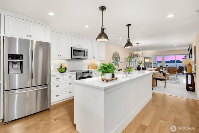 kitchen with white cabinets, stainless steel appliances, and light wood-type flooring