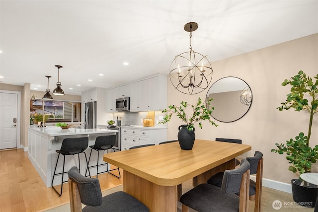 dining room with baseboards, an inviting chandelier, light wood-type flooring, and recessed lighting