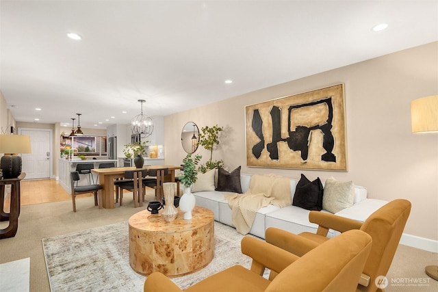 living area with recessed lighting, light colored carpet, and an inviting chandelier