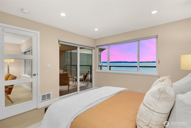 carpeted bedroom with a water view, access to outside, visible vents, and recessed lighting