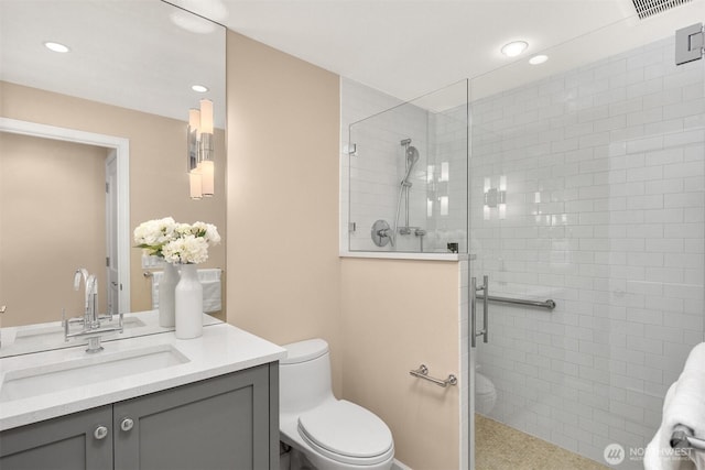 bathroom with a stall shower, toilet, visible vents, recessed lighting, and vanity