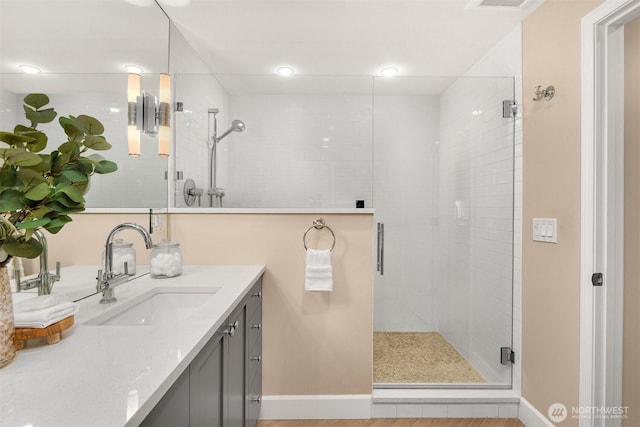 bathroom with a shower stall, baseboards, and vanity